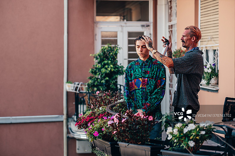 年轻男人在阳台上理发图片素材