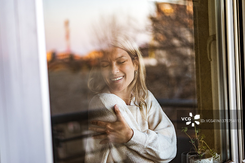 微笑的充满爱意的年轻女子拥抱自己图片素材