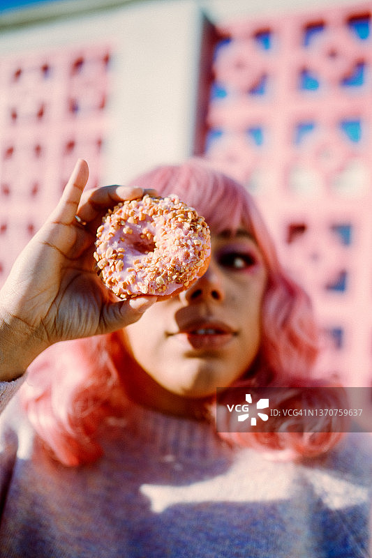 粉色头发的女人拿着粉色甜甜圈图片素材