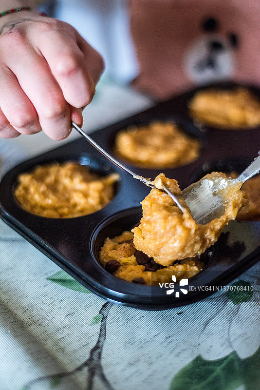 用勺子将香蕉和巧克力片混合物装入松饼烤盘图片素材