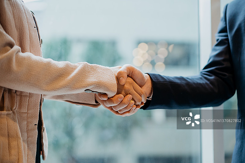 在办公室握手的亚洲女商人和男商人图片素材