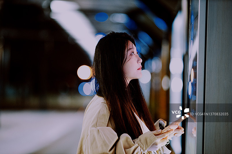 年轻的亚洲女性在车站使用触摸屏查询信息图片素材