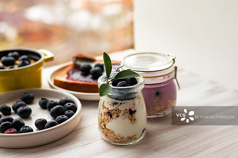 玻璃罐中的燕麦格兰诺拉麦片、混合麦片、冻糕、隔夜燕麦，烤面包，蓝莓酱图片素材