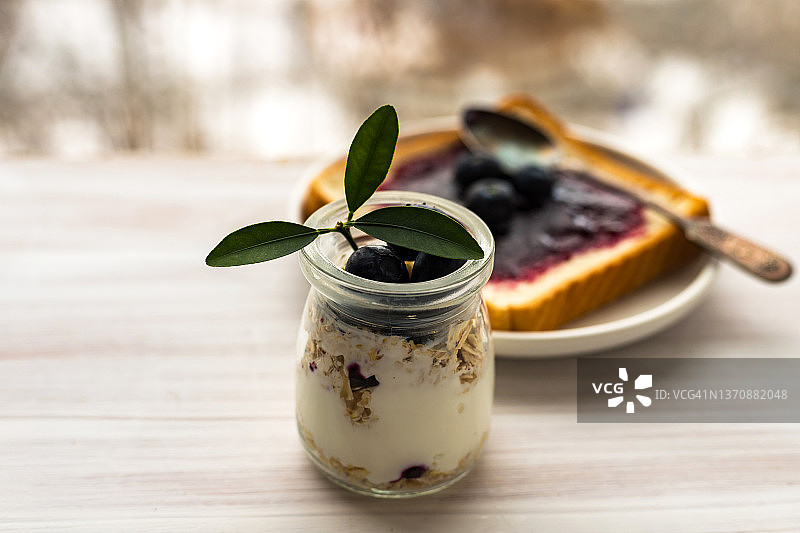 玻璃罐中的燕麦格兰诺拉麦片、混合麦片、冻糕、隔夜燕麦，烤面包，蓝莓酱图片素材