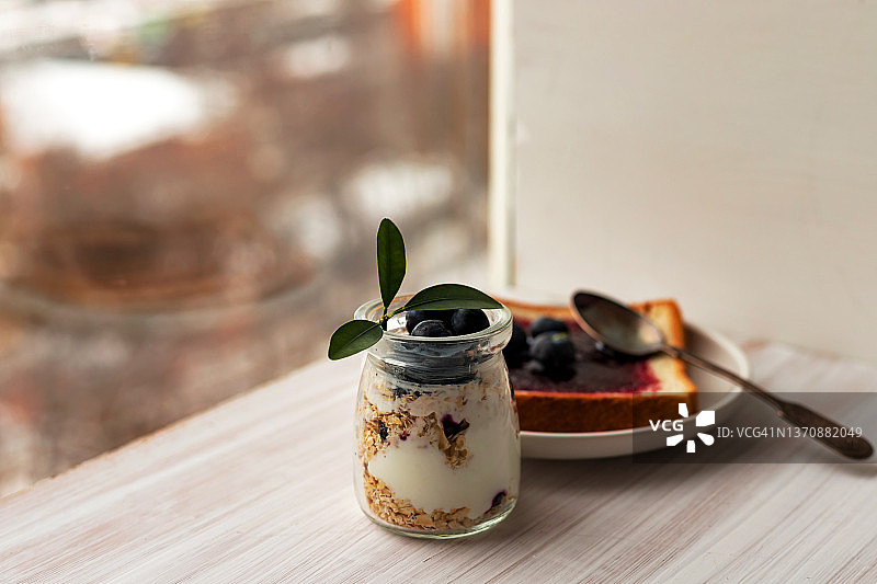 玻璃罐中的燕麦格兰诺拉麦片、混合麦片、冻糕、隔夜燕麦，烤面包，蓝莓酱图片素材