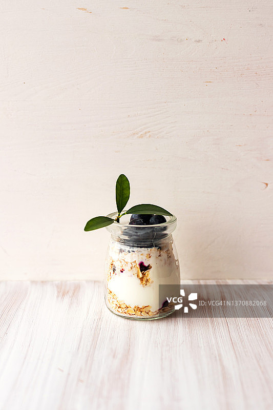 燕麦格兰诺拉麦片酸奶，蓝莓巴菲，玻璃罐装隔夜燕麦，白色桌子图片素材