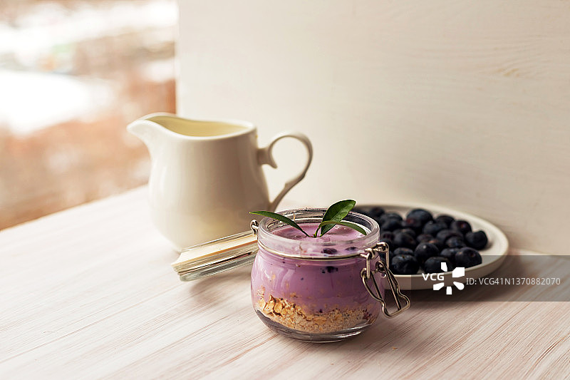 燕麦片格兰诺拉麦片或自制酸奶冰沙、新鲜蓝莓和陶瓷壶牛奶图片素材