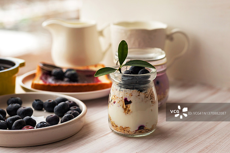 玻璃罐中的燕麦格兰诺拉麦片、混合麦片、冻糕、隔夜燕麦，烤面包，蓝莓酱图片素材