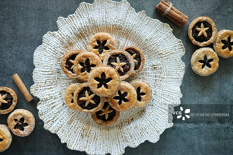 白色纹理盘子自制肉馅饼，糖粉，圣诞甜点，肉馅，肉桂棒，灰色背景图片素材