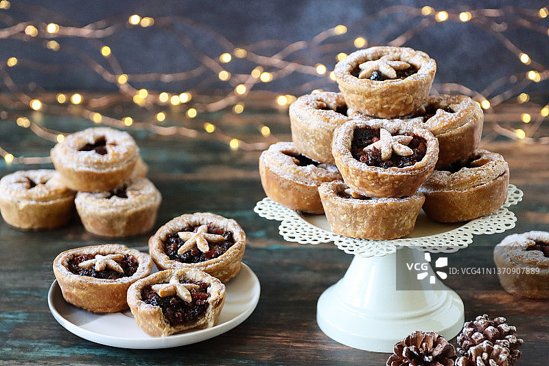 白色盘子里的自制肉馅饼，撒有糖粉，蛋糕架上摆放着甜馅饼图片素材