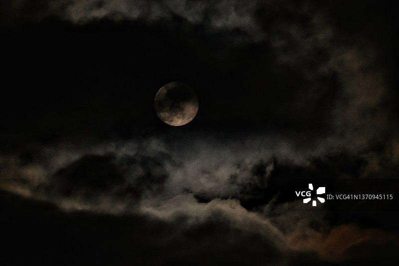 夜晚云层中隐藏的满月图片素材