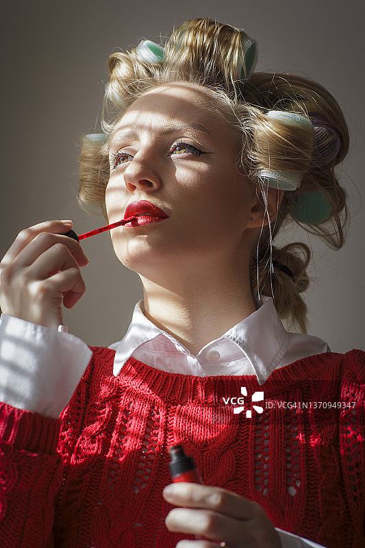 漂亮女孩在嘴唇上涂红色口红图片素材