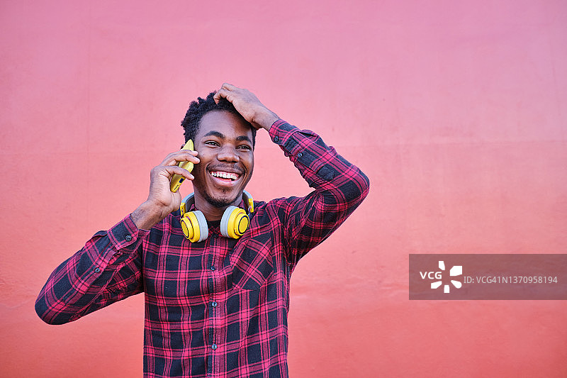 红色背景下年轻男人打电话大笑捂头图片素材