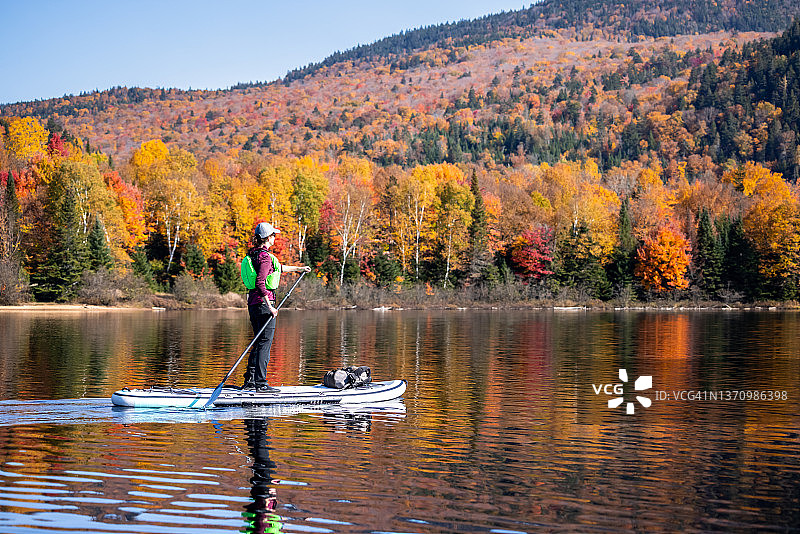 女人在加拿大魁北克省翠湖山国家公园秋季的湖上划桨板图片素材