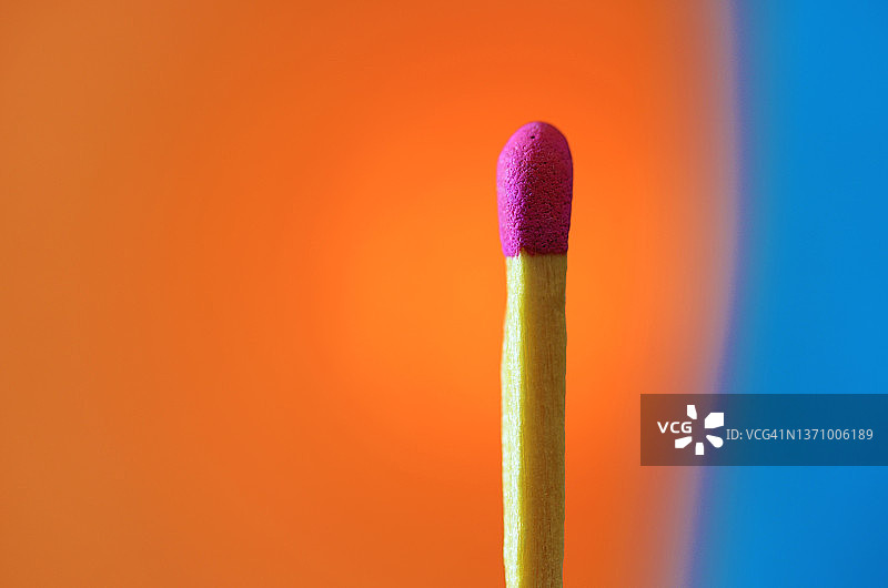 未点燃的火柴棍特写，背景为橙色和蓝色图片素材