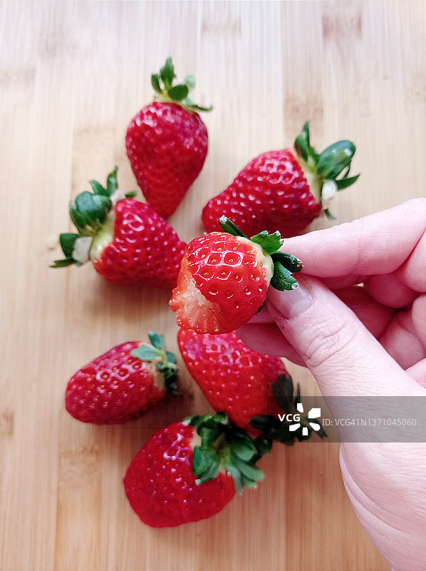 手持缺了一口的新鲜草莓图片素材