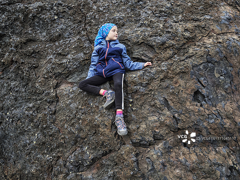 坐在西班牙加那利群岛兰萨罗特岛火山岩上的女孩图片素材