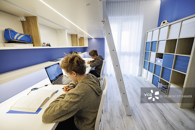 青少年男孩在房间里做作业图片素材