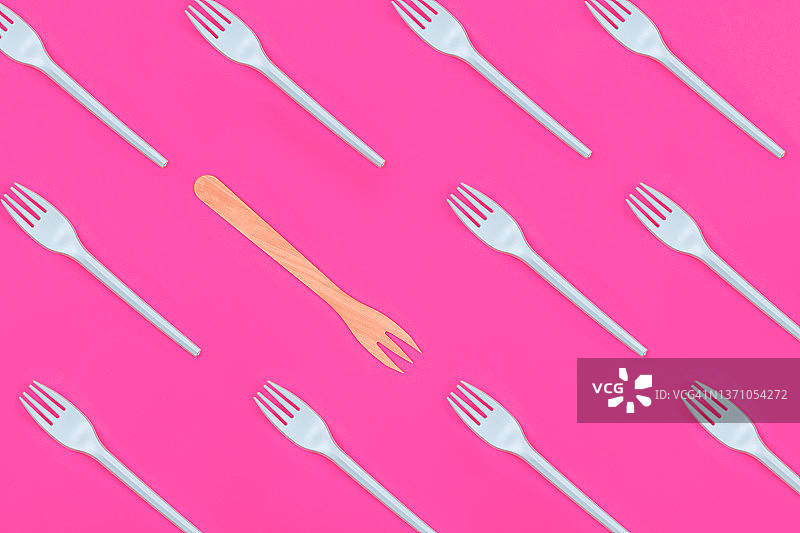 减少塑料浪费。粉色背景上的塑料叉子与木叉图片素材
