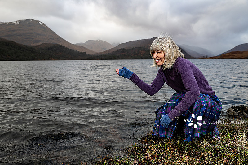 女人在苏格兰高地阿凯格湖打水漂图片素材
