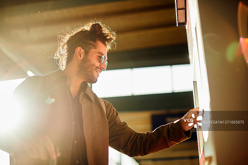 一个阳光明媚的下午，一位年轻男人购买地铁票图片素材