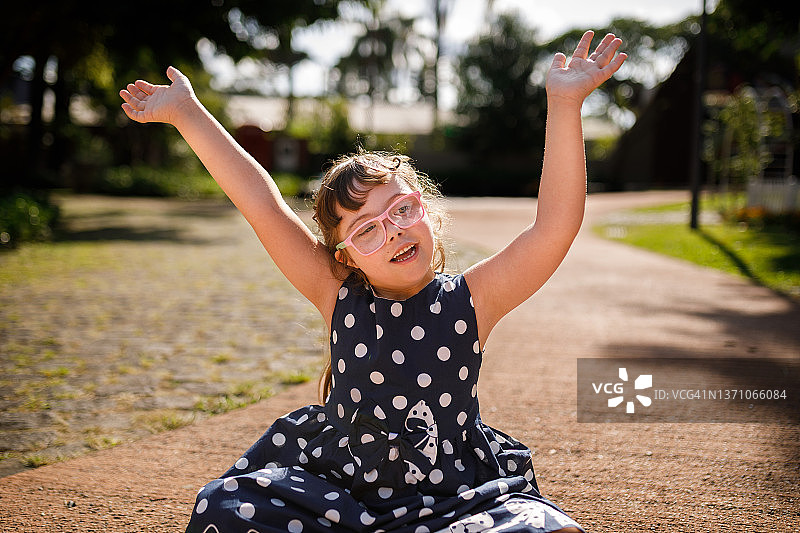 坐在地板上，张开双臂微笑的唐氏综合征女孩图片素材