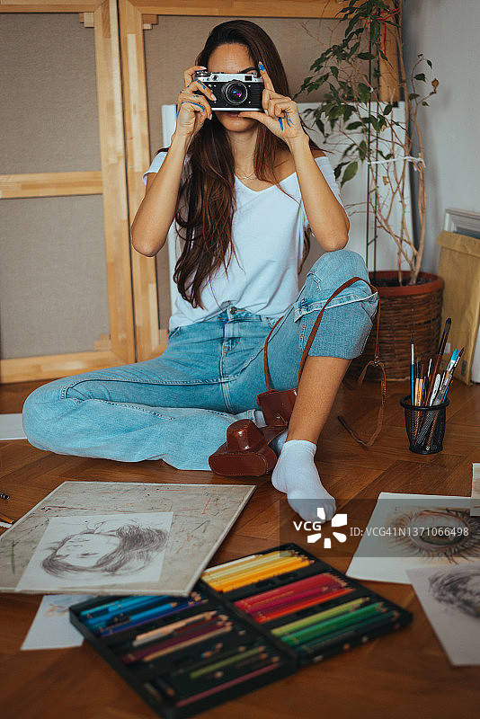 拿着复古胶片相机拍照的美丽微笑女子图片素材