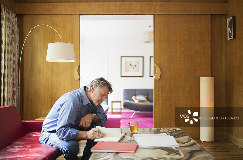 年长的男人在客厅里用笔记本工作图片素材