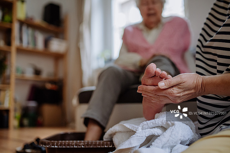 老年妇女在家接受医护人员的足部按摩图片素材