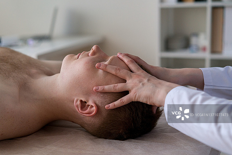 未知医生按摩病人额头：颅骨头痛，诊所预约放松治疗图片素材