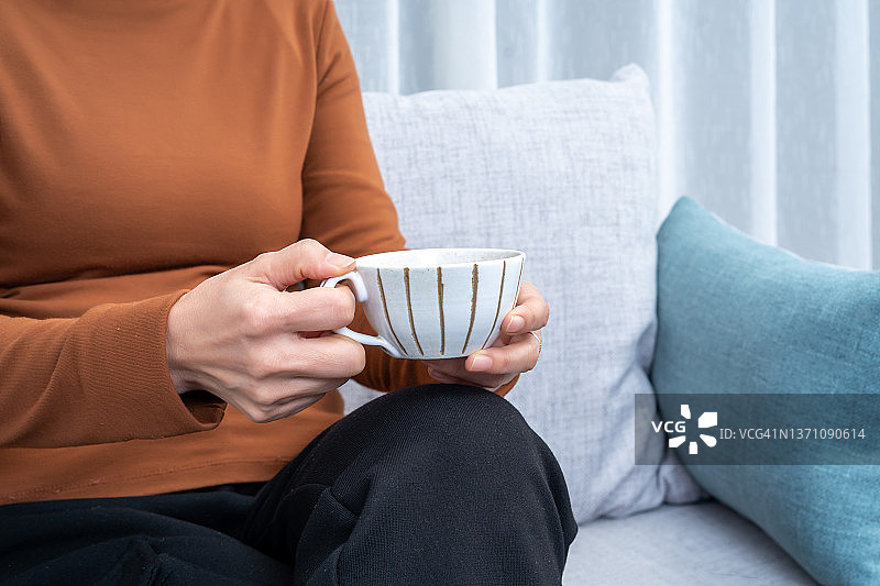 女人手捧咖啡杯坐在沙发上图片素材