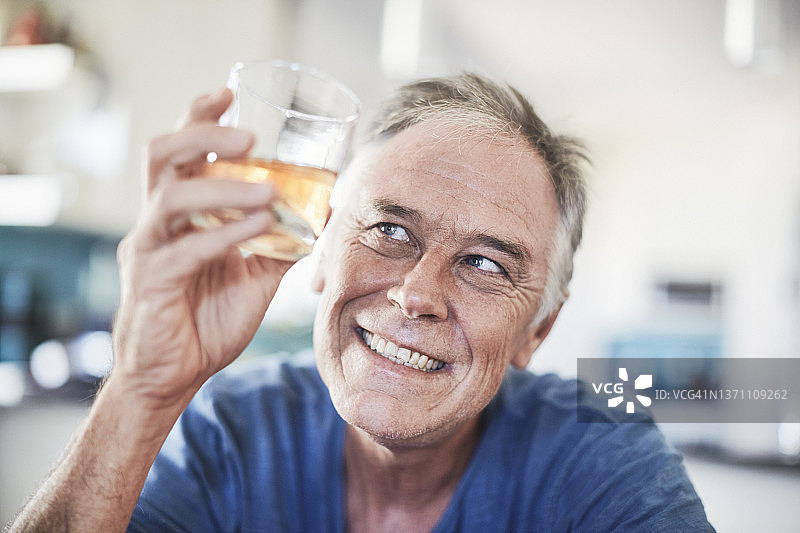 快乐的男人拿着装满威士忌、波旁威士忌、白兰地或其他琥珀色酒精饮料的玻璃杯图片素材