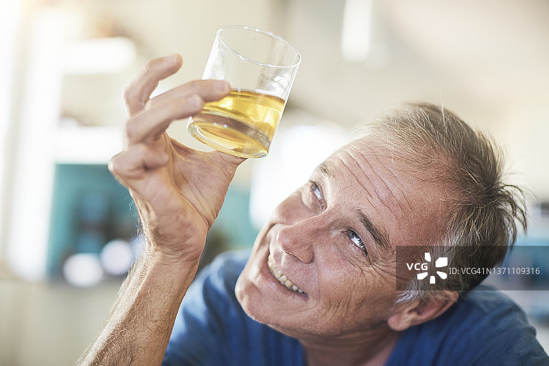 快乐的男人拿着装满威士忌、波旁威士忌、白兰地或其他琥珀色酒精饮料的玻璃杯图片素材