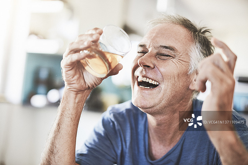 快乐的男人拿着装满威士忌、波旁威士忌、白兰地或其他琥珀色酒精饮料的玻璃杯图片素材