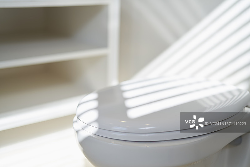 浴室白色马桶座上的阳光阴影图片素材