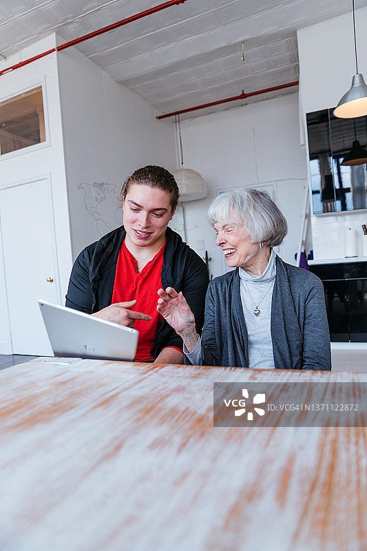 年长的女人在孙子的指导下学习使用平板电脑图片素材