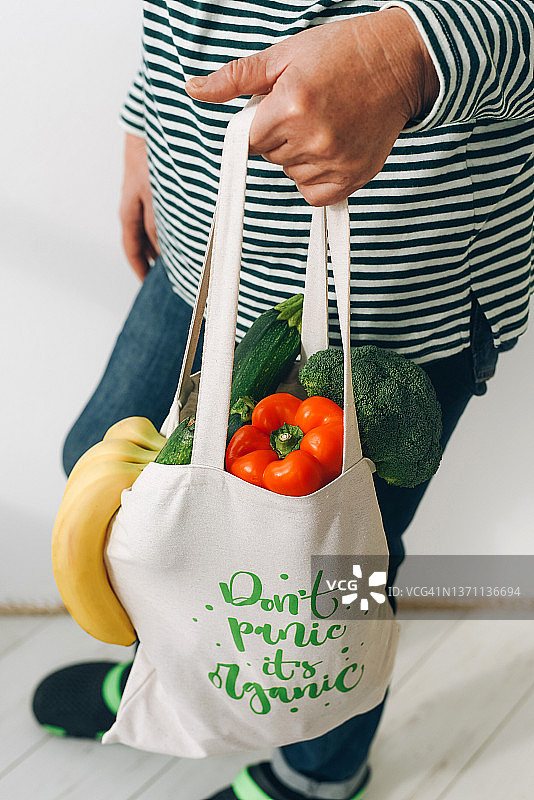 一名女子携带装满水果和蔬菜的白色购物袋图片素材