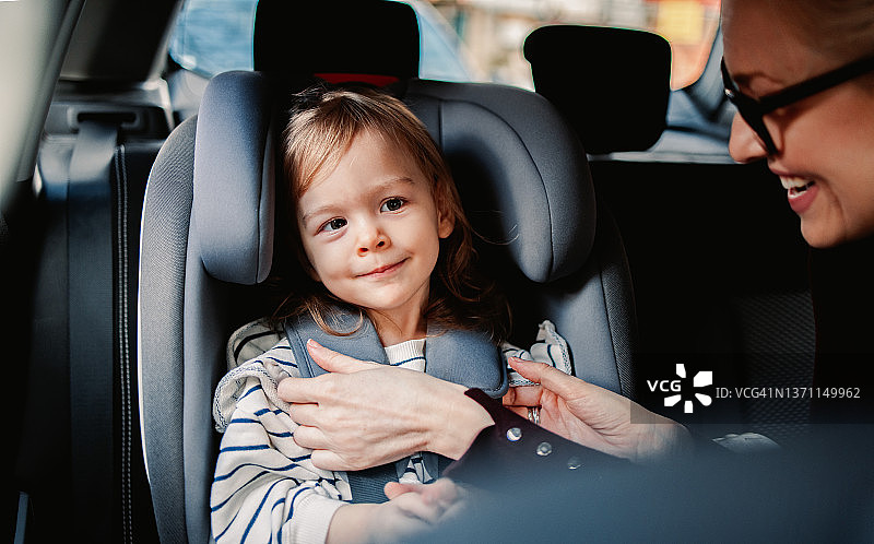 快乐的父母在车里为孩子系安全带图片素材