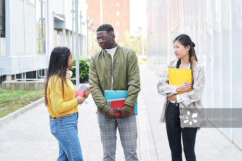 三名国际学生在大学校园里讨论作业的照片图片素材