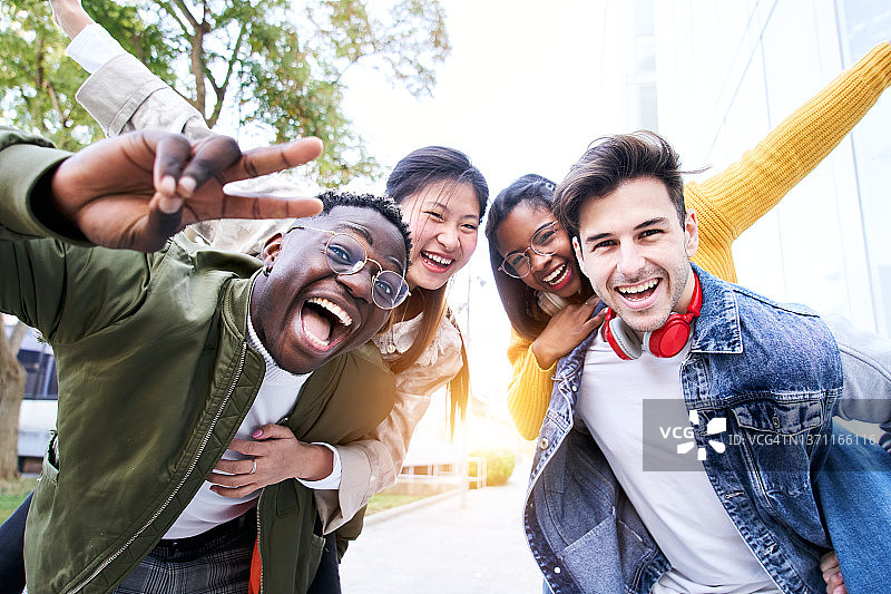 四个朋友快乐地玩耍，男人背着女人的肖像图片素材