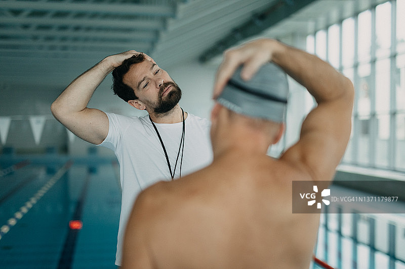 私人教练在室内游泳池与年长游泳者一起锻炼图片素材