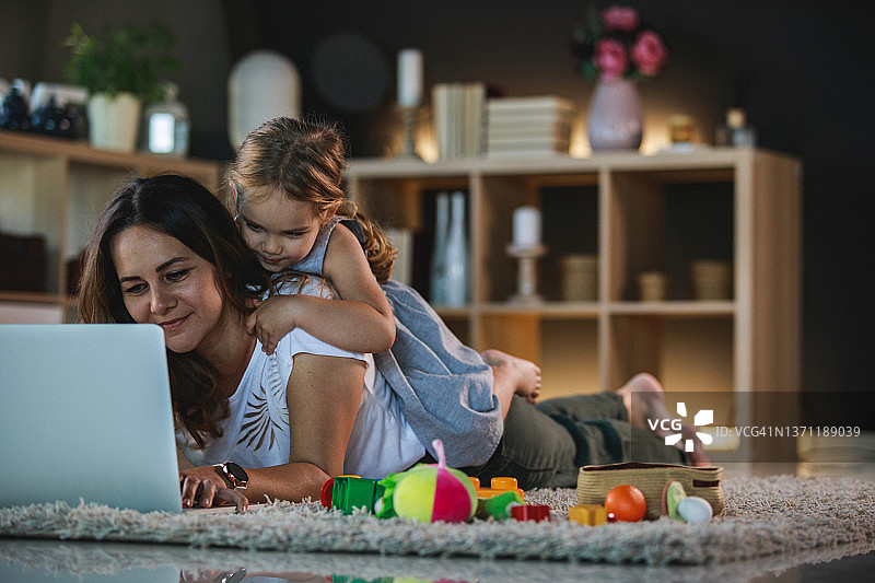 小女孩依偎着在家工作的母亲图片素材