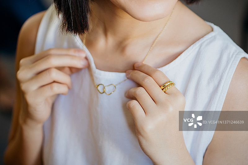 试戴金色项链的年轻亚裔美女肖像图片素材