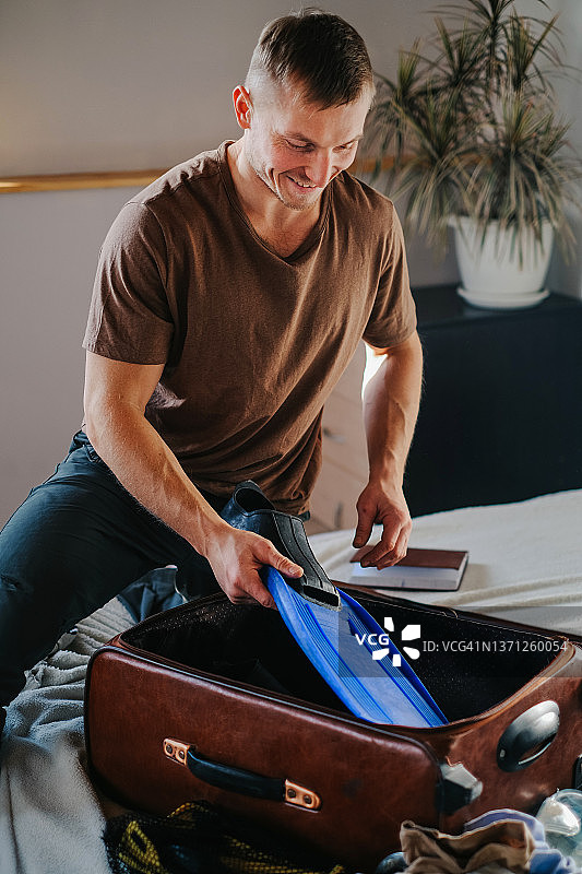 快乐的男人收拾旅行行李箱图片素材