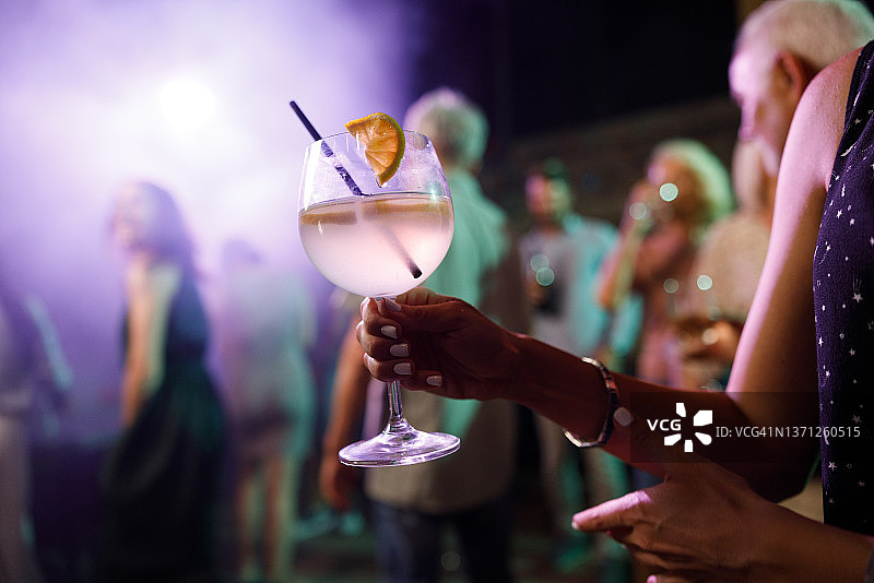 夜晚在俱乐部，女人拿着鸡尾酒特写图片素材