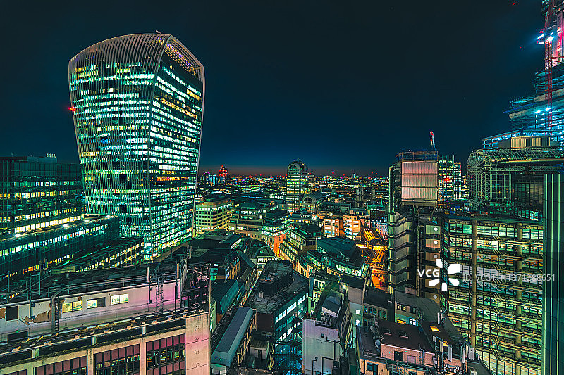 夜晚，伦敦城市天际线上方的现代玻璃建筑，办公室灯火通明图片素材