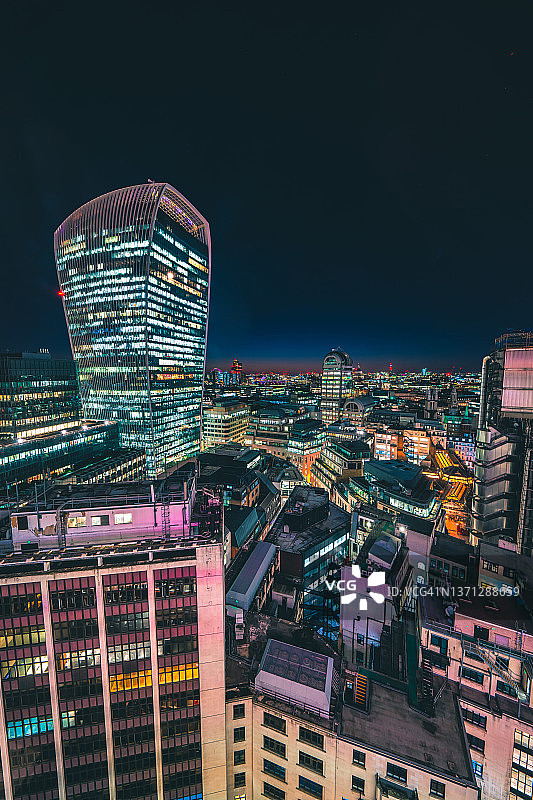 夜晚，伦敦城市天际线上方的现代玻璃建筑，办公室灯火通明图片素材