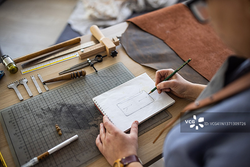 皮革匠人在工作室为钱包绘制草图图片素材