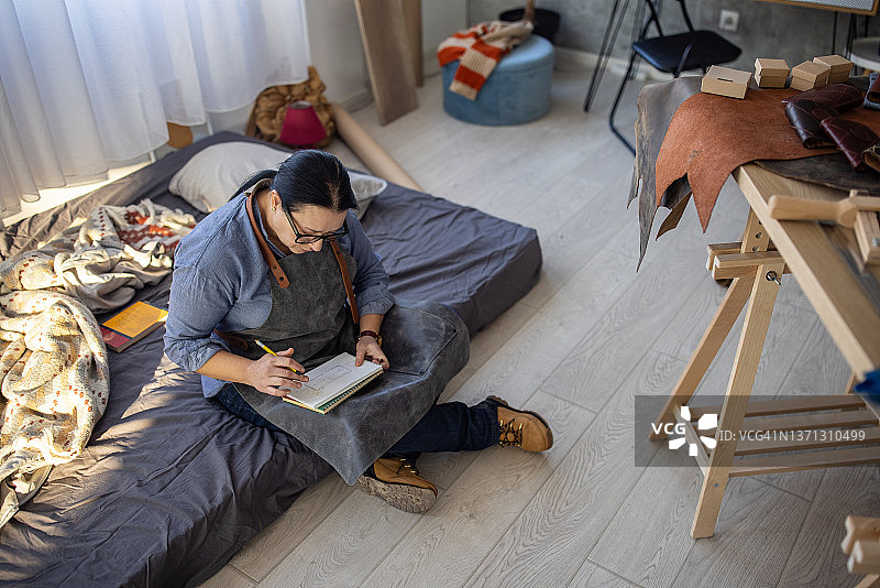 女性皮革匠在工作室绘制定制皮革钱包草图图片素材