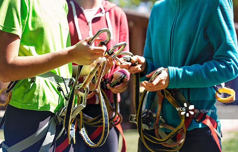 一群青少年（或母女）准备在滑索公园度过冒险的一天。图为安全锁的特写图片素材